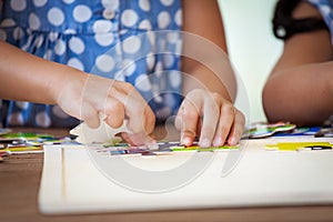 Child little girl hand trying to connect jigsaw puzzle piece