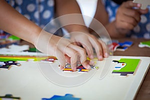 Child little girl hand trying to connect jigsaw puzzle piece