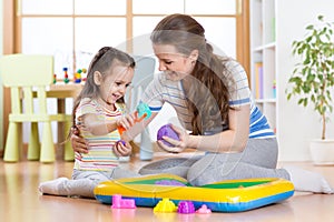 Child little girl and mother playing with kinetic sand at home photo