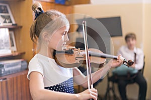 Child, little girl playing violin indoors in music class