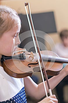 Child, little girl playing violin indoors in music class. vertical photo