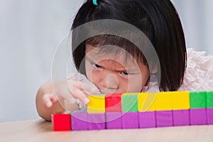 Child little girl playing wooden toys at home or kindergarten school. Kid is seriously sorting and building the wooden blocks.