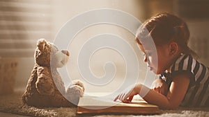 Child little girl reading a magic book in dark home