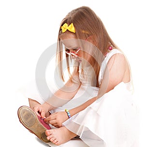 Child little girl tries to put on her shoes isolat