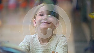 Child, Little Girl Watching, Looking Fishes in an Aquarium in Mall. Pet shop. Girl looks at fish swimming in aquarium