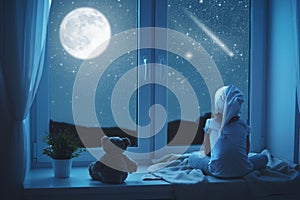 Child little girl at window dreaming and admiring starry sky at