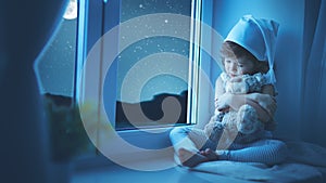 Child little girl at window dreaming and admiring the starry sky