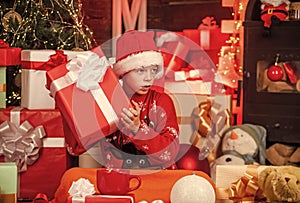 Child little happy boy find gifts near christmas tree. Gifts shop. Kid santa hat christmas gift boxes. Merry christmas