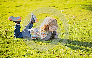 Child liyng outdoor. Kid in park. Spring Boy lie down on grass. Summer walk. Children adaptation.