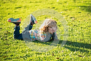 Child liyng outdoor. Kid in park. Spring Boy lie down on grass. Summer walk. Children adaptation.