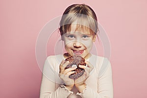 Child llittle girl holding donut on pastel pink background