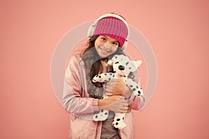 Child long curly hair. cosy winter season. pet care. warm clothes for cold weather. happy little girl play dog toy. pink