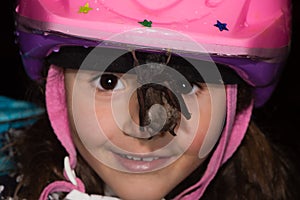 Child looking at bat hanging from helmet