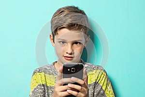 Child looking at a cell phone with a surprised look on his face