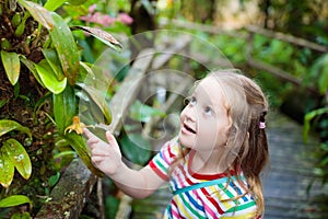 Child looking at flower in jungle.