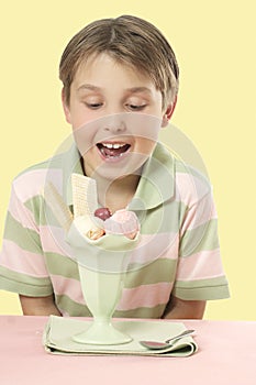 Child looking at an ice cream sundae on a table.