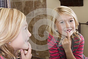 Child looking in mirror at missing front tooth