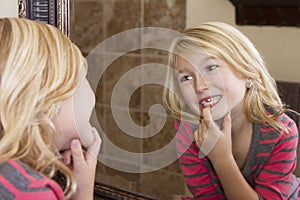 Child looking in mirror at missing front tooth