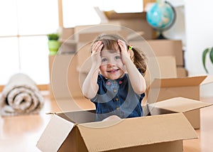 Child looking out of a box in new room after moving