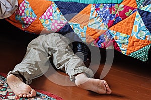 Child looking for something under the bed.