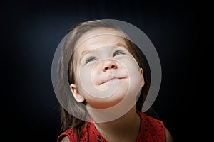 Child looking up on dark background. little girl smiling and looking with amazing