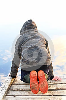 A child looking into water with a mirror reflection of the sky