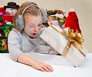Child looks in a box with a gift on Christmas.
