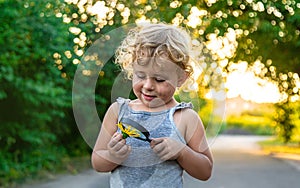 A child looks at a flower with a magnifying glass. Selective focus.