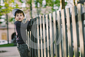 The child looks through the hole in the fence