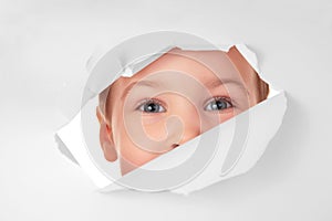 Child looks in hole in sheet of paper