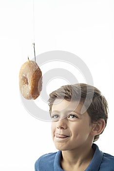 A child looks longingly at a doughnut hanging from a hook photo