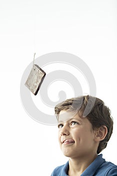 A child looks longingly at a sponge cake hanging from a hook photo
