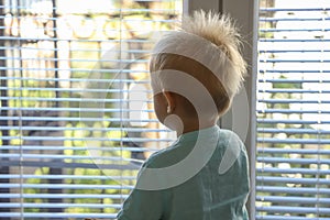 Child looks out the window and waits for the cancellation of quarantine, wants to go outside