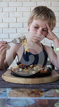 The child looks at the roast. There is no appetite. The girl doesn`t want to eat. The concept of lack of appetite