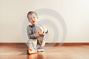 Child with lots of independence sitting on the floor putting on his socks with an expression of effort