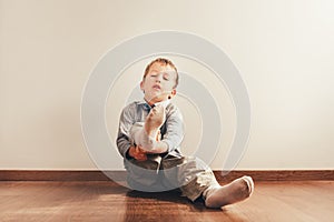 Child with lots of independence sitting on the floor putting on his socks with an expression of effort