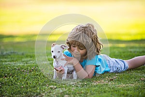 Child lovely embraces his pet doggy. Kid boy with dog relaxing on nature.