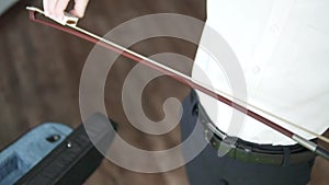 A child lubricates the bow with rosin before playing the violin