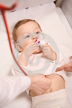 Child lying in cot being examined by neonatologist with stethoscope photo