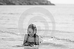 Child lying in surf in black and white