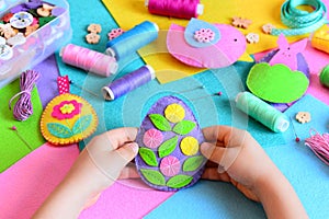 Child made Easter egg decor from felt. Small child holds a felt Easter egg decor in his hands. Easter crafts set