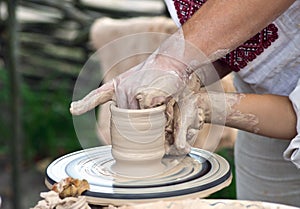 Child make a pitcher on a pottery wheel
