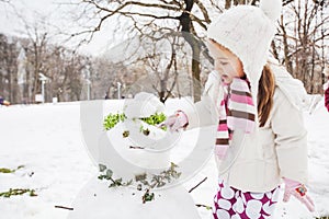 Child Make A Snowman In The Park At Winter Day