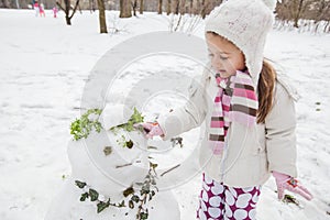 Child Make A Snowman In The Park At Winter Day