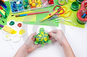 The child makes a craft toy from foam plastic tortoise. Material for creativity and education