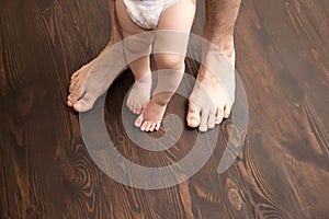 The child makes the first step. Large male legs with small baby legs. Dad helps the child take the first steps