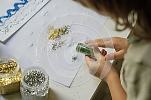 Child makes funny art work using glitter