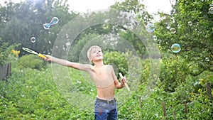 Child making big soap bubbles outdoors
