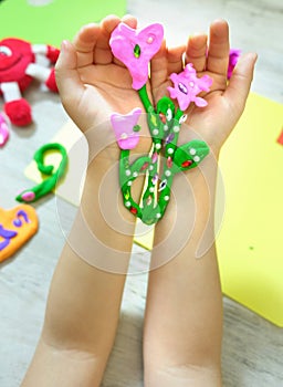 Child making bouquet, flowers from plasticine, clay, beads. little girl creating gift for mom gift for Mothers day, Birthday or