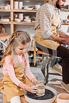 child making ceramic pot on pottery wheel with teacher